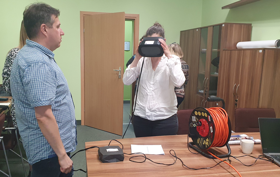 Foto: Frau mit Virtual-Reality-Brille, daneben steht ein Mann, auf dem Tisch weitere Technik