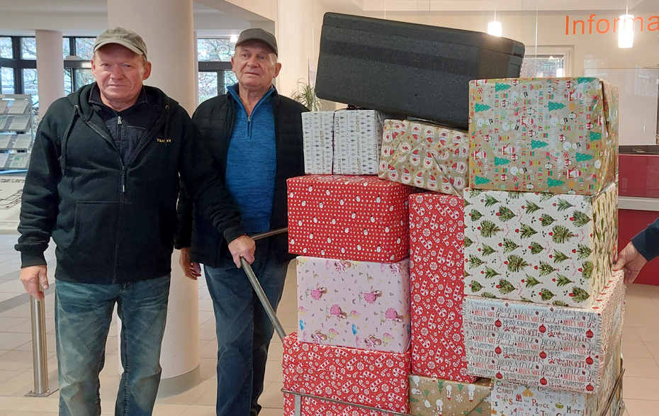 Foto: zwei Männer mit einem Wagen voller Weihnachtspäckchen