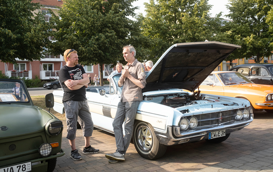 Foto: 2 Männer fachsimpeln neben einem Oldtimer