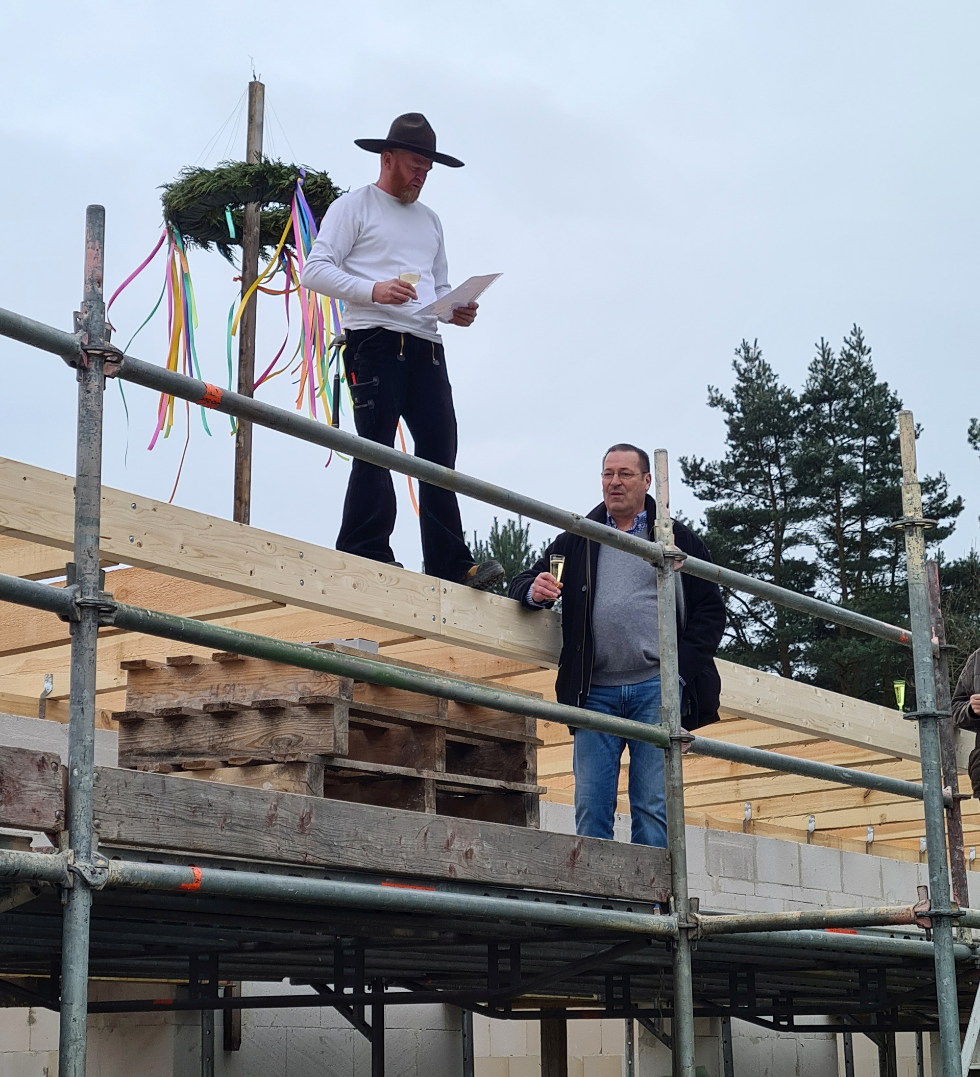 Foto: 2 Männer auf dem Dach mit Richtkrone