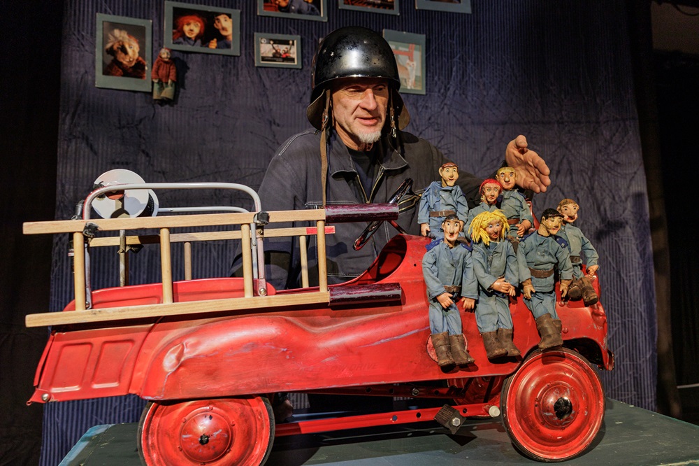 Foto: Puppenspieler präsentiert eine Feuerwehr mit 7 Puppen darauf