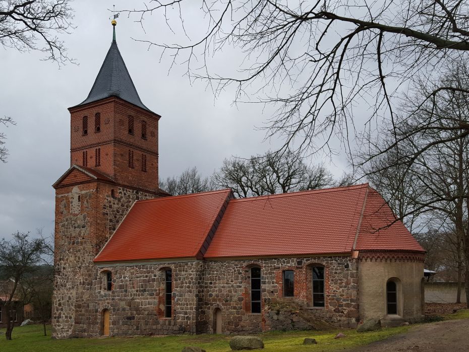 Feldsteinkirche mit Anbau, halbrunder Apsis und aufgesetztem viereckigen Backsteinturm