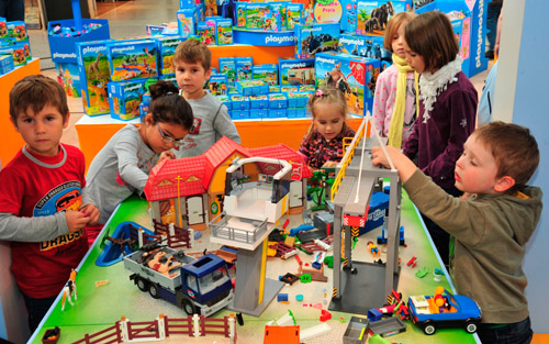 Foto: Sieben Kinder spielen am Tisch mit Playmobil-Steinen.