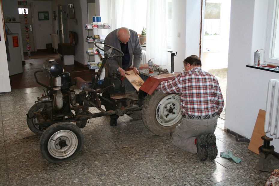 Zwei Männer schrauben an einem Traktor.