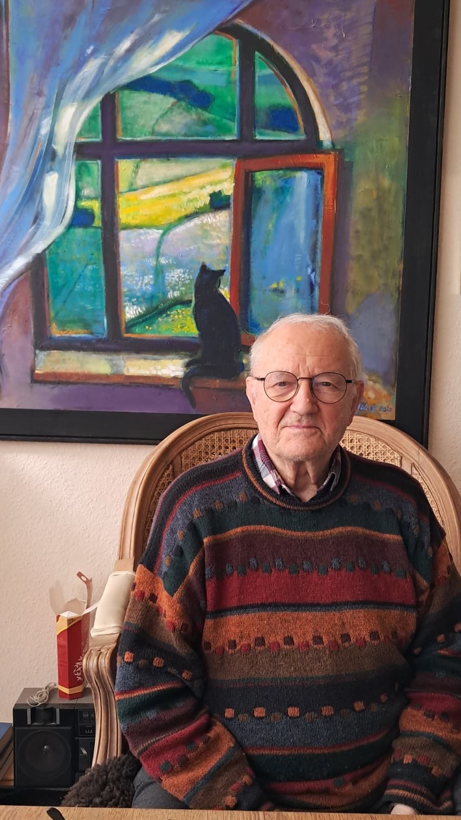 Foto: sitzender Künstler vor einem seiner Werke