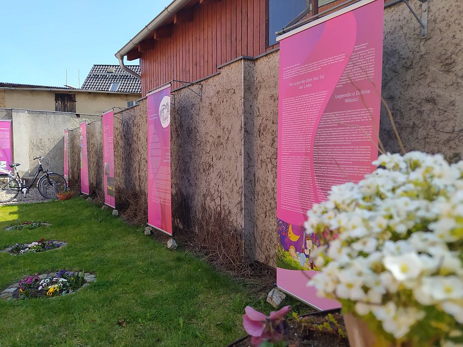 Ausstellunsgbanner vor einer Wand im Garten