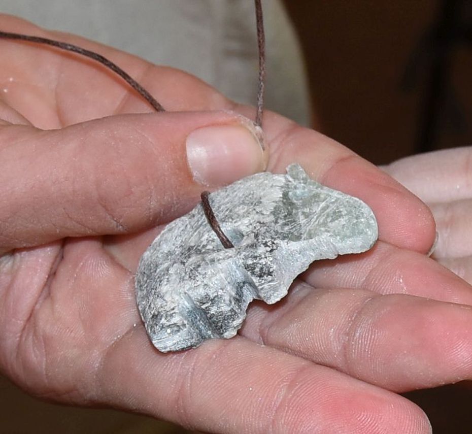 Tierfigur aus Speckstein als Anhänger liegt auf einer Hand