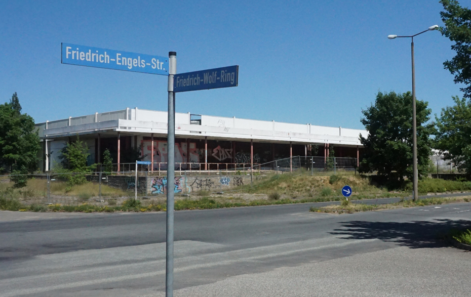 Foto: abrissreife Kaufhalle, davor das Straßenschild Friedrich-Engels-Str. und Friedrich-Wolf-Ring