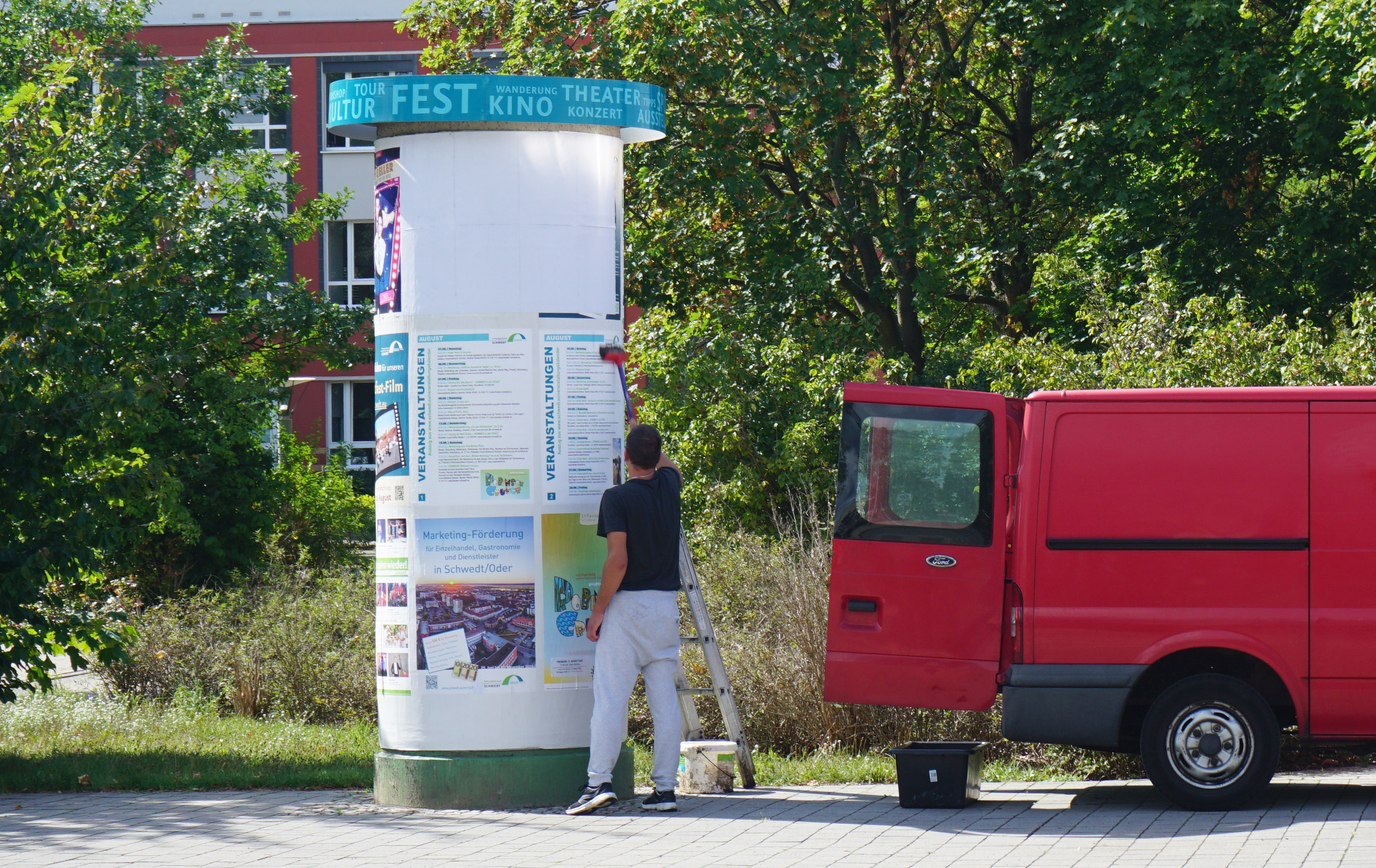 Foto: Dienstleister klebt Plakate an die Litfaßsäule