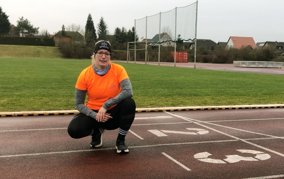 Foto: hockende Frau auf einer Sportplatzlaufbahn