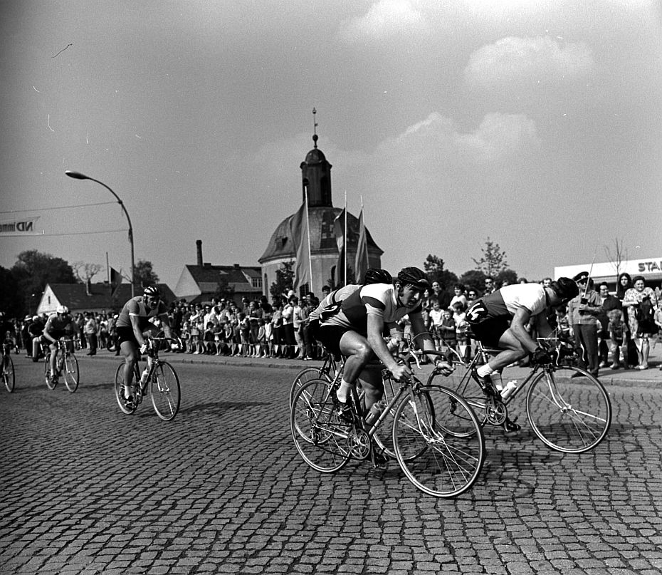 Viele Menschen stehen am Straßenrand, um die Rennradfahrer zu sehen.