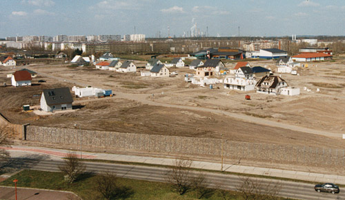 Foto: Baugebiet mit ersten Häusern und unfertigen Straßen und Mauern