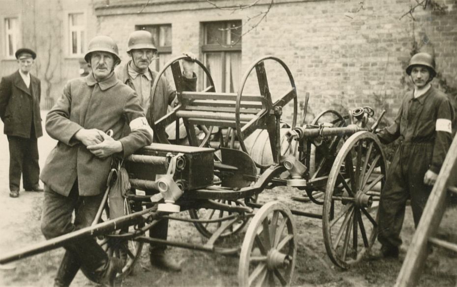 Gruppe von Feuerwehrmännern mit Löschspritze