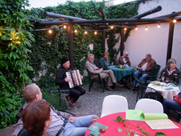 Foto: Im Museumshof sitzen Gäste und lauschen dem Akkordeonspieler.