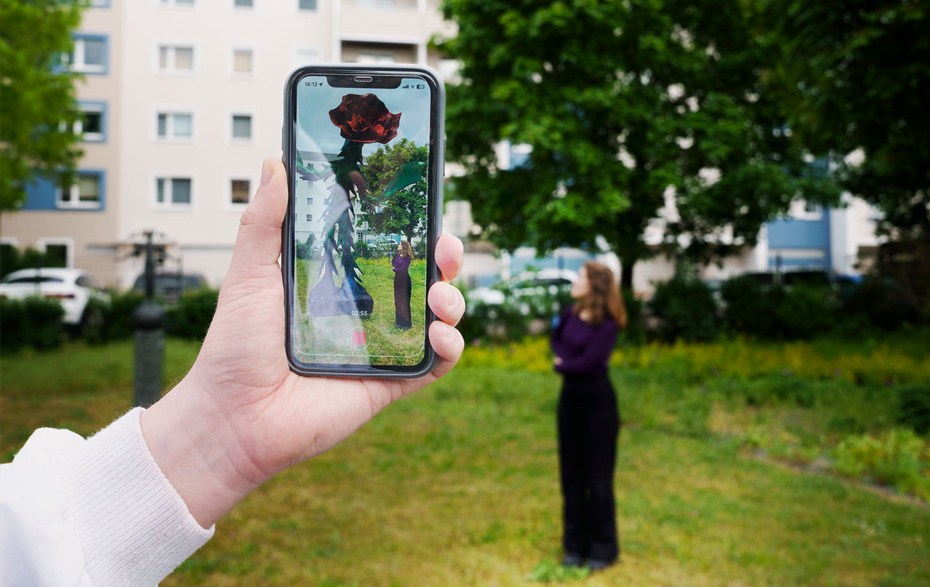 Foto: Auf dem Handy in der Hand ist ein Kunstwerk zu sehen, dass ist real nicht gibt.