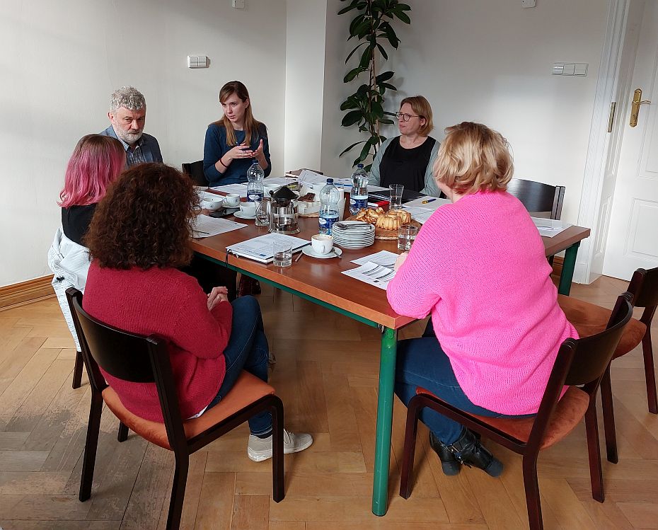 Frauen und Männer sitzen an einem Tisch.