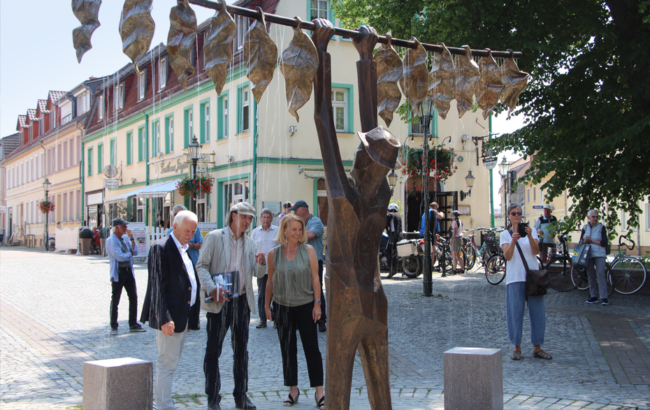 Foto: Bürgermeister, Künstler und Fachbereichsleiterin vor dem sprudelnden Brunnen