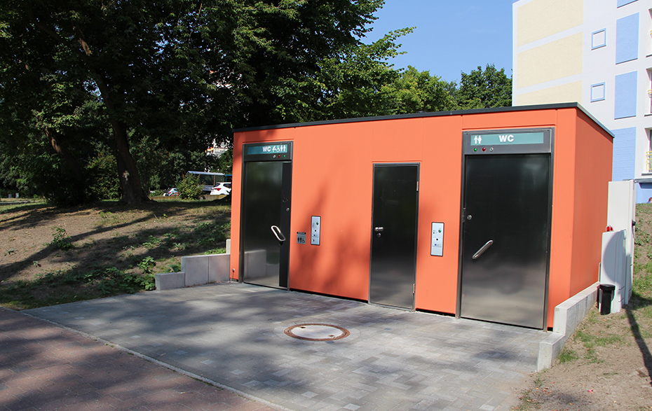 Toilettenhäuschen und dahinter das Hochhaus am Uferweg