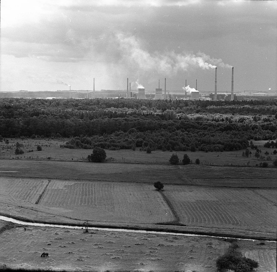 Blick über Felder auf Industriebauten, Türme