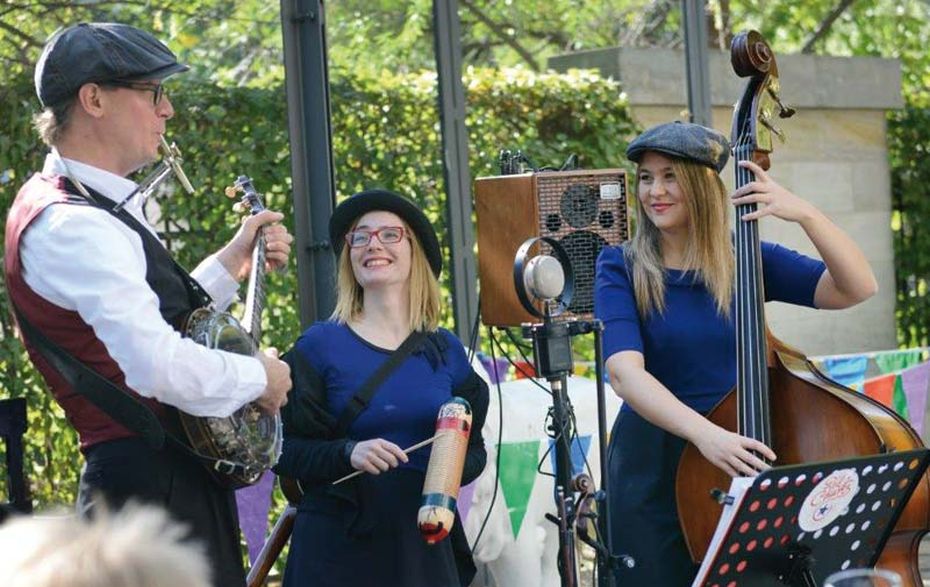 Ein Mann und zwei Frauen machen Musik. Sie spielen Open-Air.