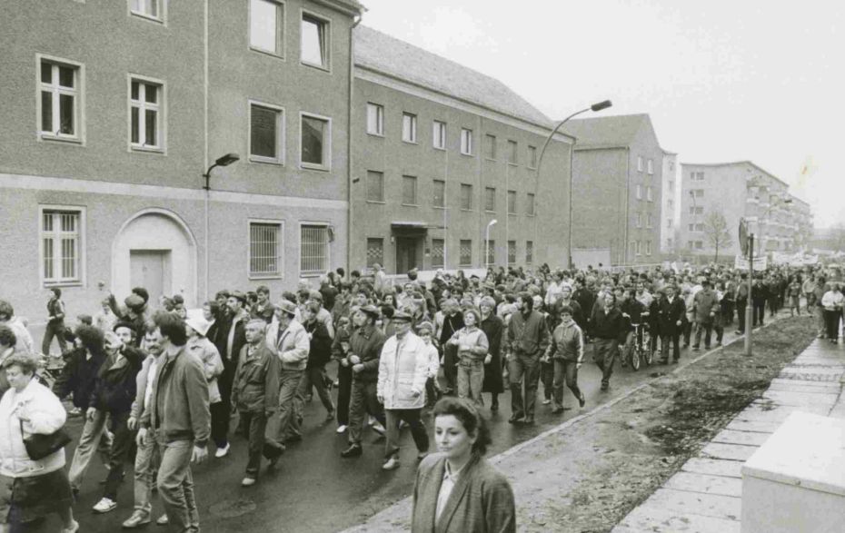 Viele Menschen laufen aus Protest auf der Straße an dem Staatssicherheitsgebäude vorbei.