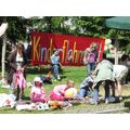 Foto: Kinder sitzen auf Decken, im Hintergrund ein Banner mit der Aufschrift „Kinderflohmarkt“