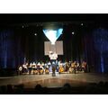 Foto: Orchester spielt und ein Heißluftballon-Atrappe schwebt auf die Bühne.