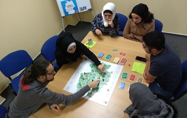 Foto: 4 Frauen und 2 Männer beim gemeinsamen Spiel sitzen am einen Tisch herum