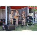 Drei Männer in G.I. Uniform stehen unter einem Dach im Garten des Museums. singen und spielen auf Saxophon und Gitarren.