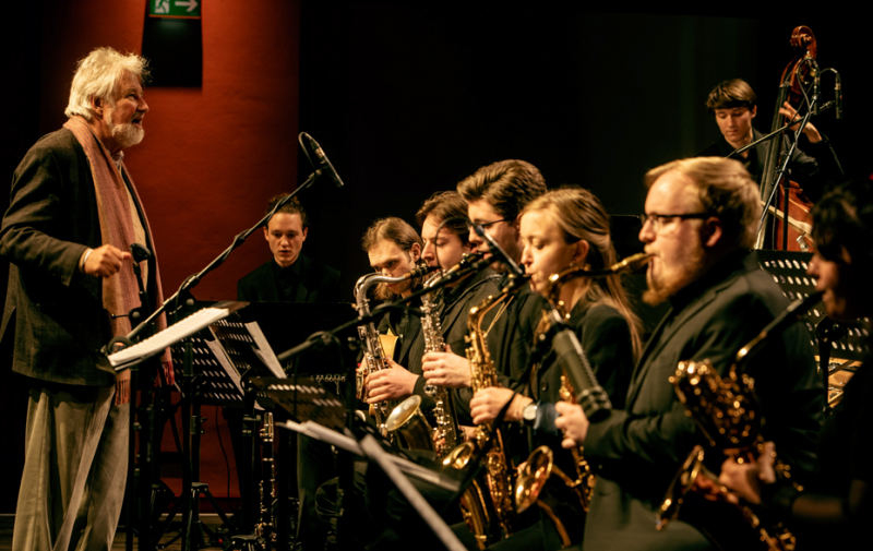 Foto: junge Musikerinnen und Musiker mit Dirigent