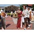 Foto: Winkende Frauen, Männer und Kinder laufen im Kreis auf dem Festplatz ein-im Hintergrund die Erntekrone aus Tabakpflanzen