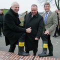 Foto: Zwei Männer halten Gummistiefel mit Aufkleber in die Kamera.