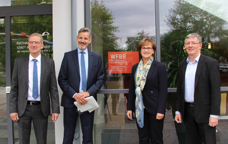 Gruppenfoto: 4 Personen vor rotem Schild