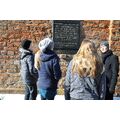 Gruppe steht vor einer Mauer mit einer Tafel.