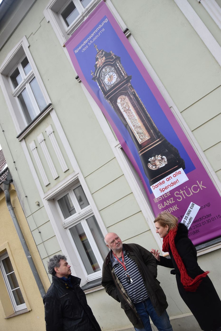 Zwei Männer und eine Frau stehen vor dem Museum und reden.