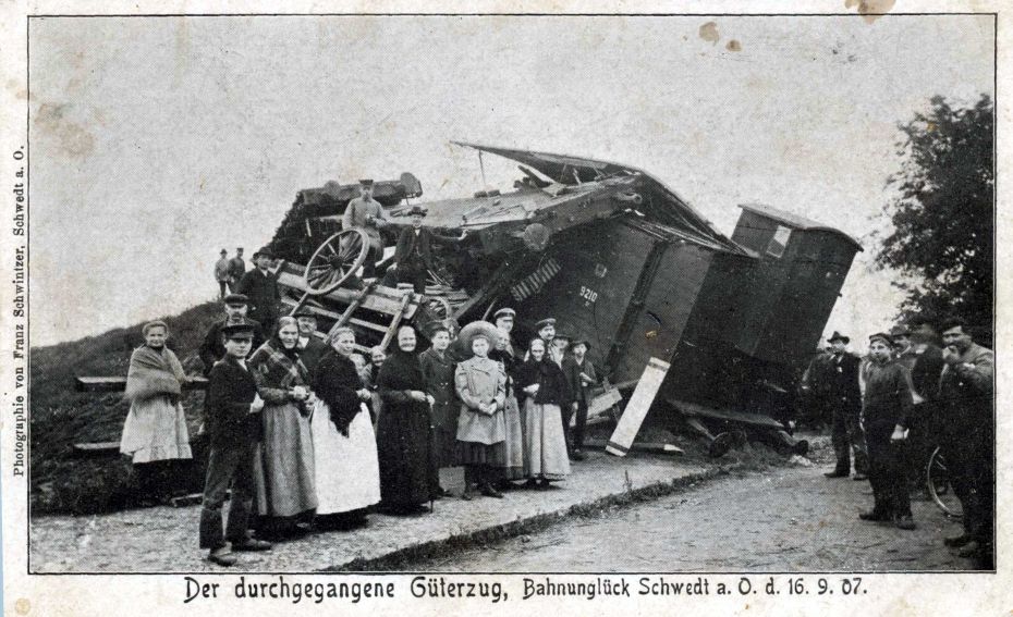 Viele Menschen stehen vor einer umgestürzten Lokomotive.